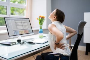 NYC Physical Therapy - Lady With Back Pain Sitting at a Desk