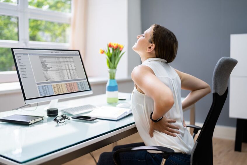 NYC Physical Therapy - Lady With Back Pain Sitting at a Desk